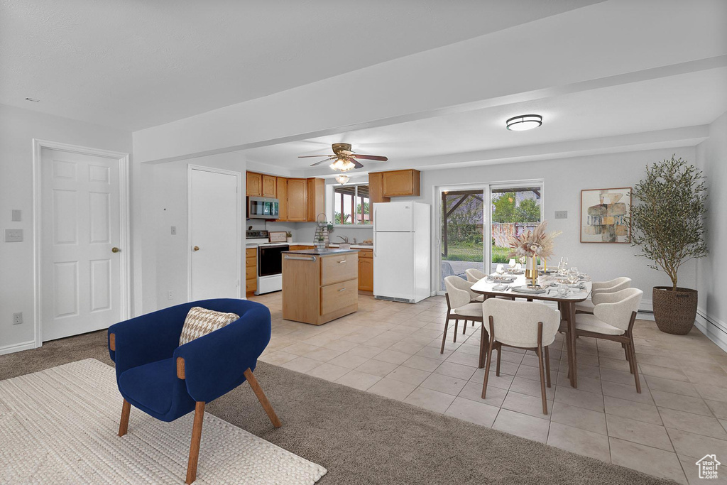 Dining space with light tile patterned flooring, ceiling fan, light colored carpet, and baseboards