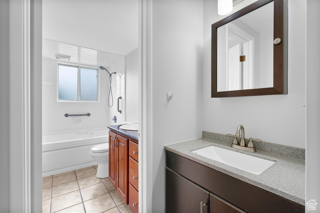 Bathroom with vanity, toilet, tile patterned flooring, and shower / tub combination