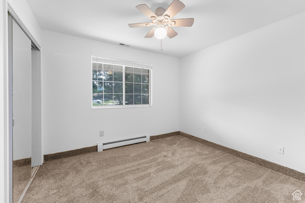 Unfurnished bedroom featuring a baseboard heating unit, carpet flooring, a closet, ceiling fan, and baseboards