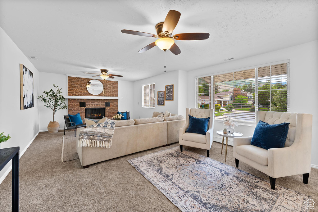 Carpeted living area with ceiling fan, a fireplace, and baseboards