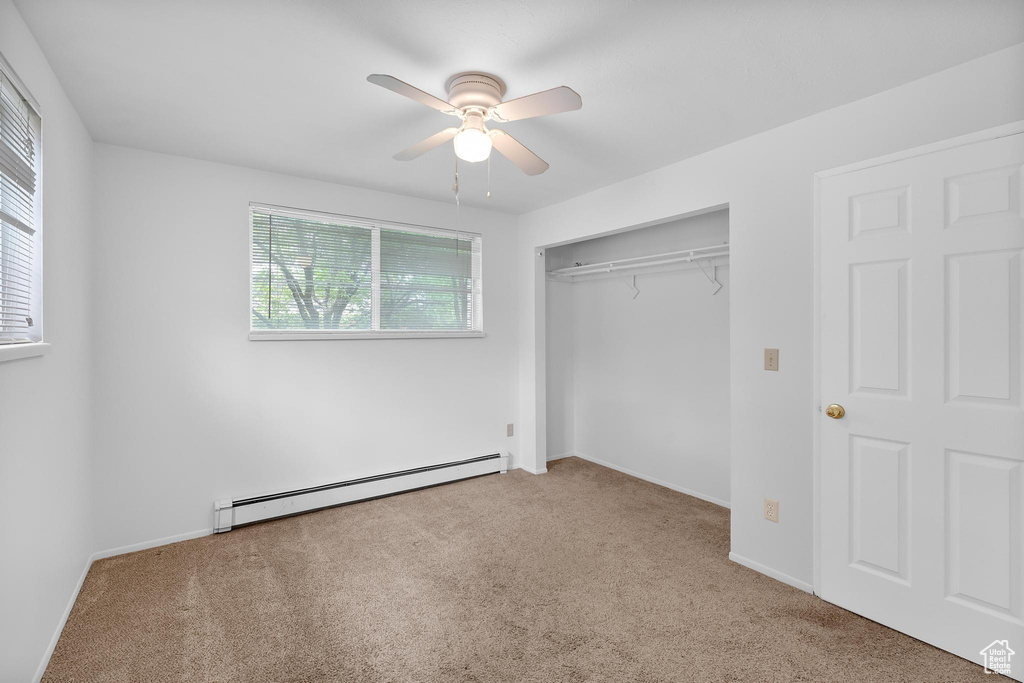 Unfurnished bedroom with a baseboard radiator, carpet, a closet, and baseboards