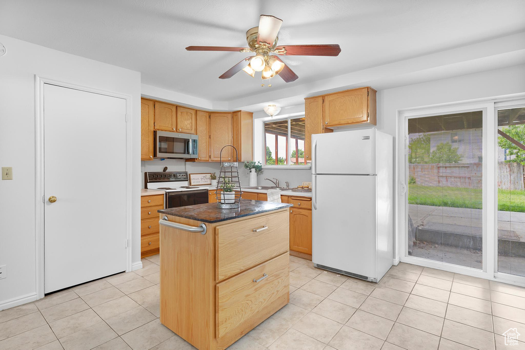 Kitchen with freestanding refrigerator, stainless steel microwave, electric stove, a ceiling fan, and light tile patterned flooring