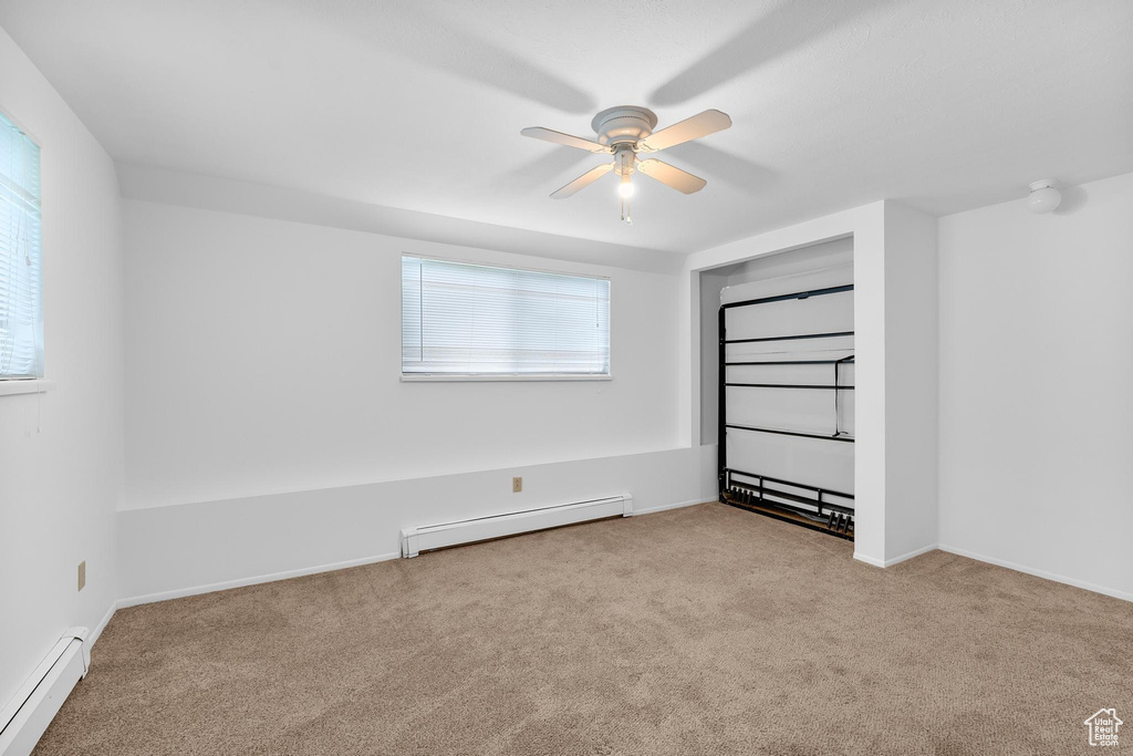 Unfurnished bedroom with baseboard heating, carpet, and ceiling fan