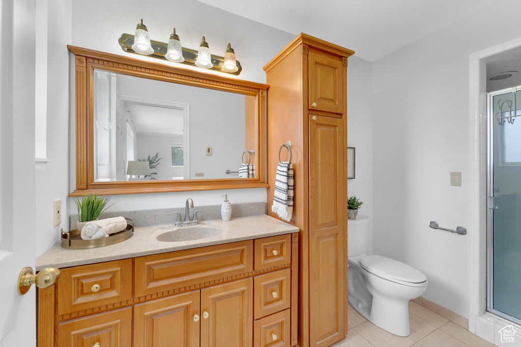 Full bathroom featuring toilet, tile patterned floors, vanity, and an enclosed shower