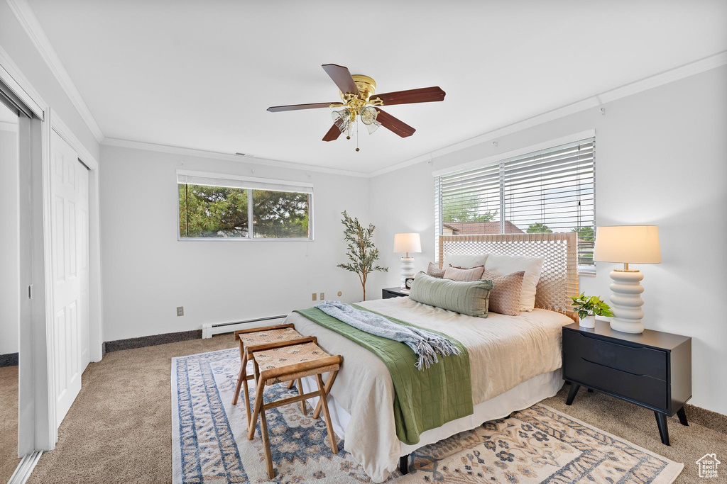 Bedroom with a baseboard radiator, light colored carpet, multiple windows, crown molding, and a ceiling fan