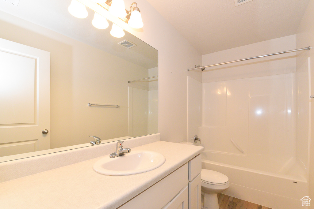Full bath with toilet, wood finished floors, vanity, and shower / washtub combination