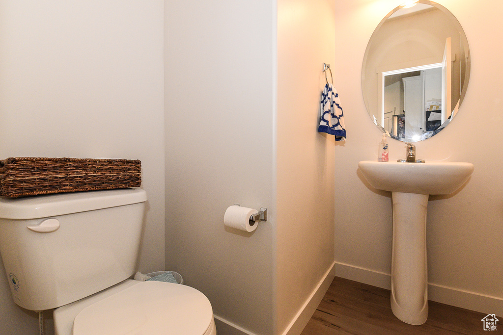 Bathroom featuring toilet, wood finished floors, and baseboards