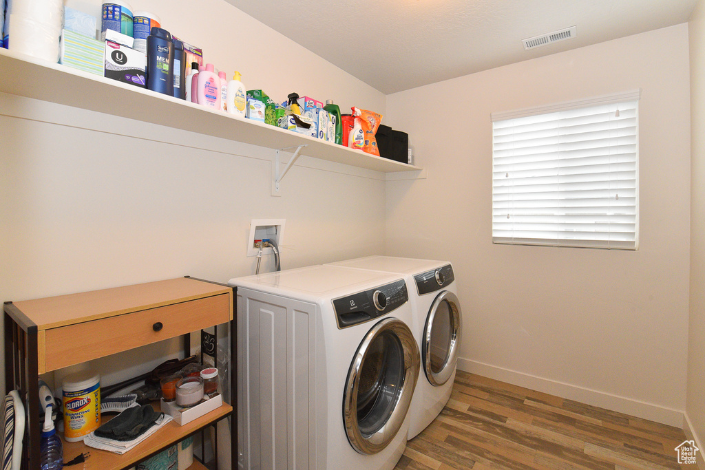 Laundry room with separate washer and dryer, light wood-style flooring, and baseboards
