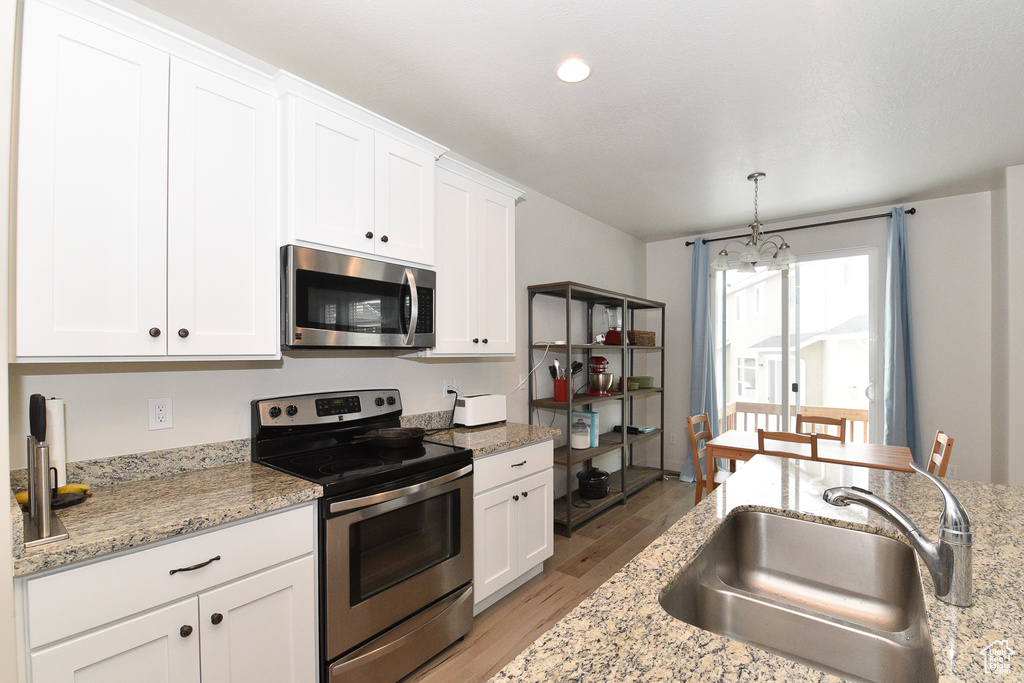 Kitchen featuring stainless steel appliances, a sink, light wood finished floors, white cabinets, and recessed lighting