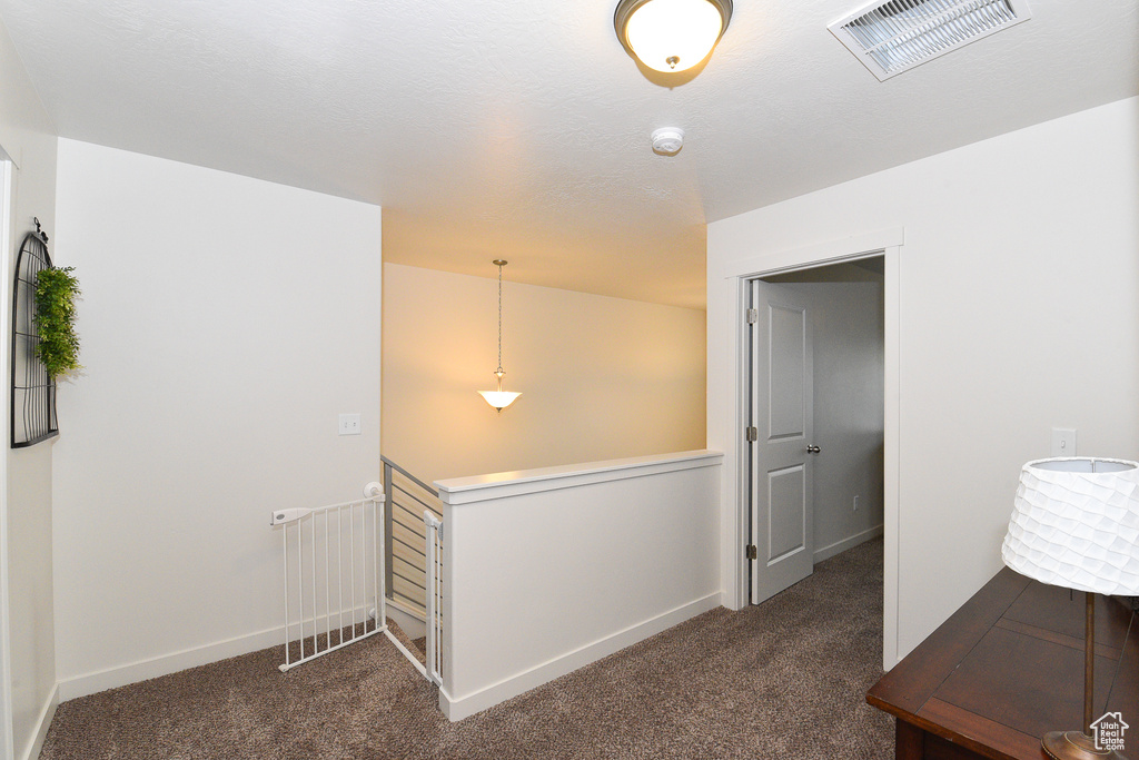 Corridor featuring dark carpet, an upstairs landing, and baseboards