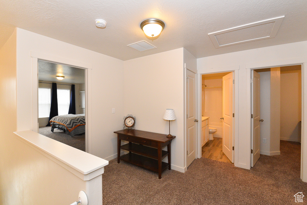 Corridor featuring attic access, carpet flooring, and baseboards