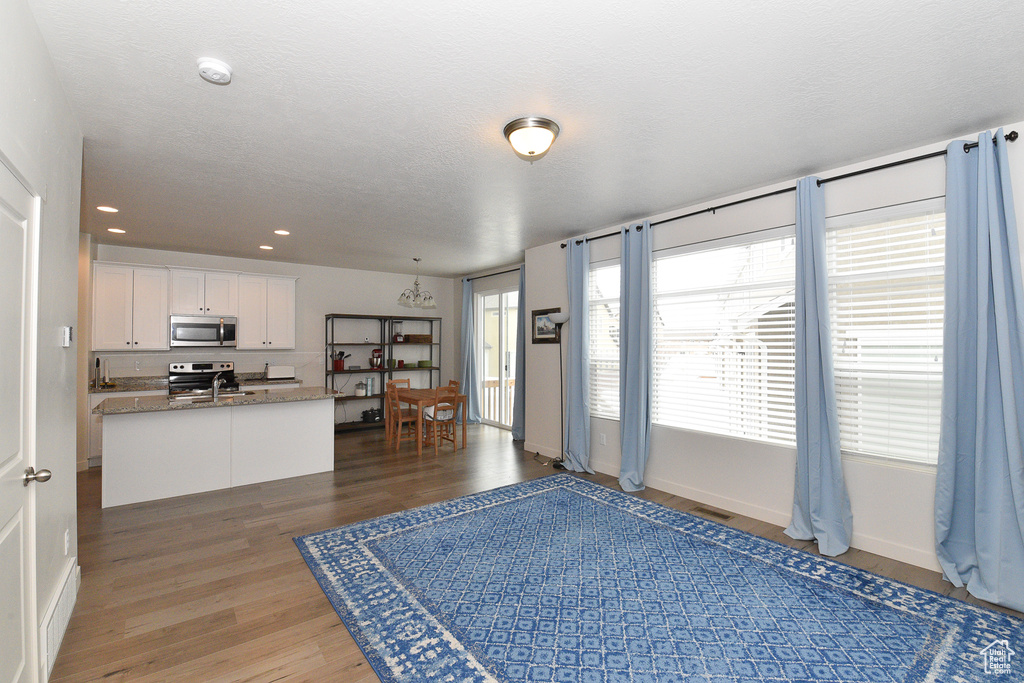 Kitchen with appliances with stainless steel finishes, light wood-style flooring, white cabinets, baseboards, and recessed lighting