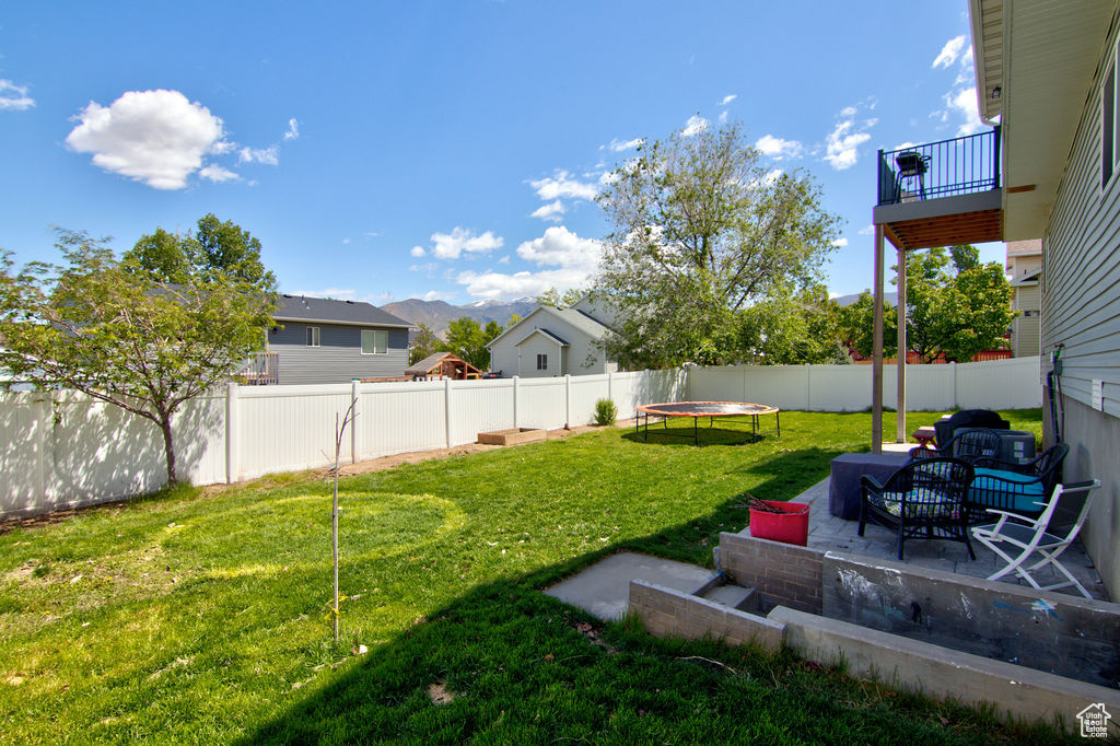View of yard with a trampoline and a patio