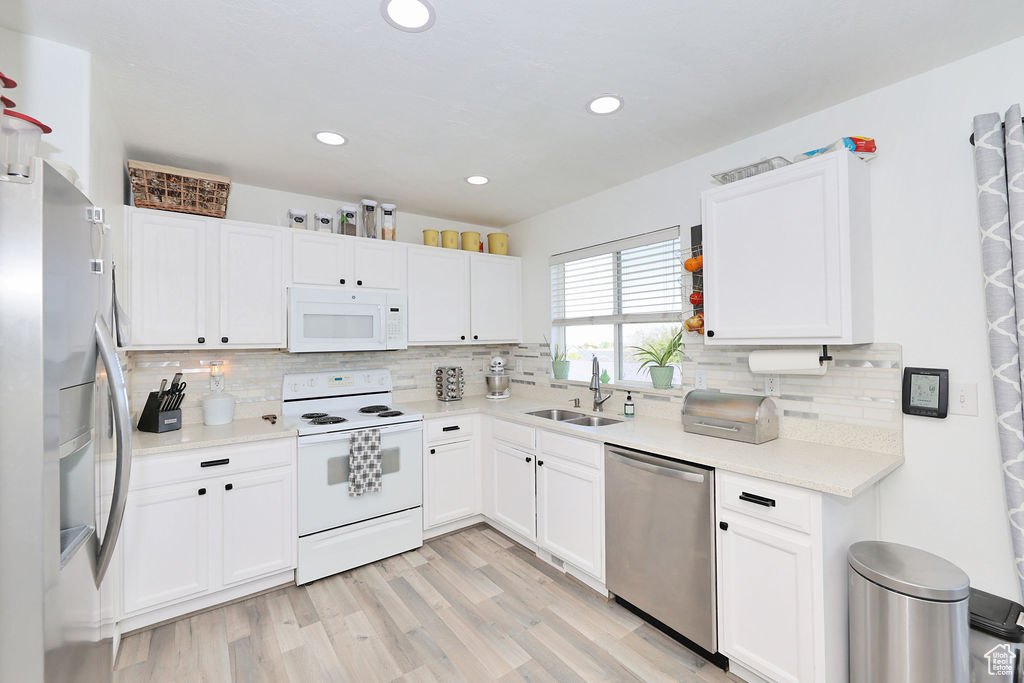 Kitchen featuring stainless steel appliances, a sink, tasteful backsplash, white cabinets, and recessed lighting