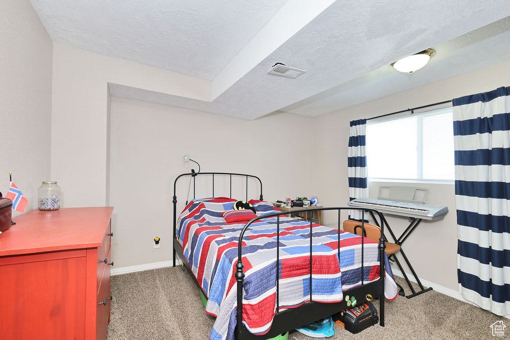 Bedroom with carpet floors, baseboards, and a textured ceiling