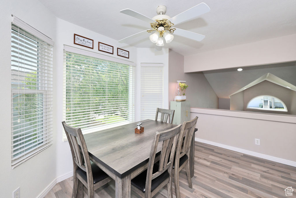 Dining space with a ceiling fan, wood finished floors, baseboards, and lofted ceiling