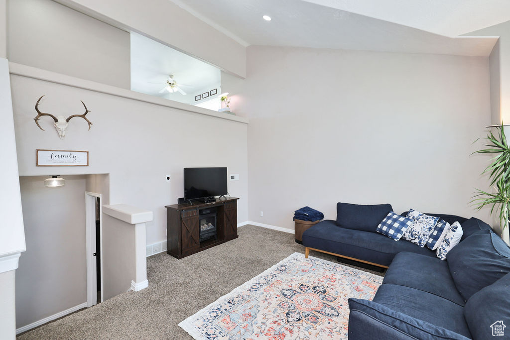 Living area with carpet flooring, lofted ceiling, ceiling fan, and baseboards