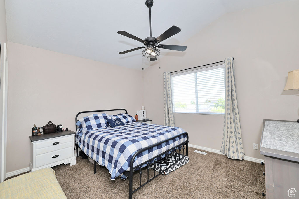 Bedroom with lofted ceiling, carpet floors, baseboards, and ceiling fan