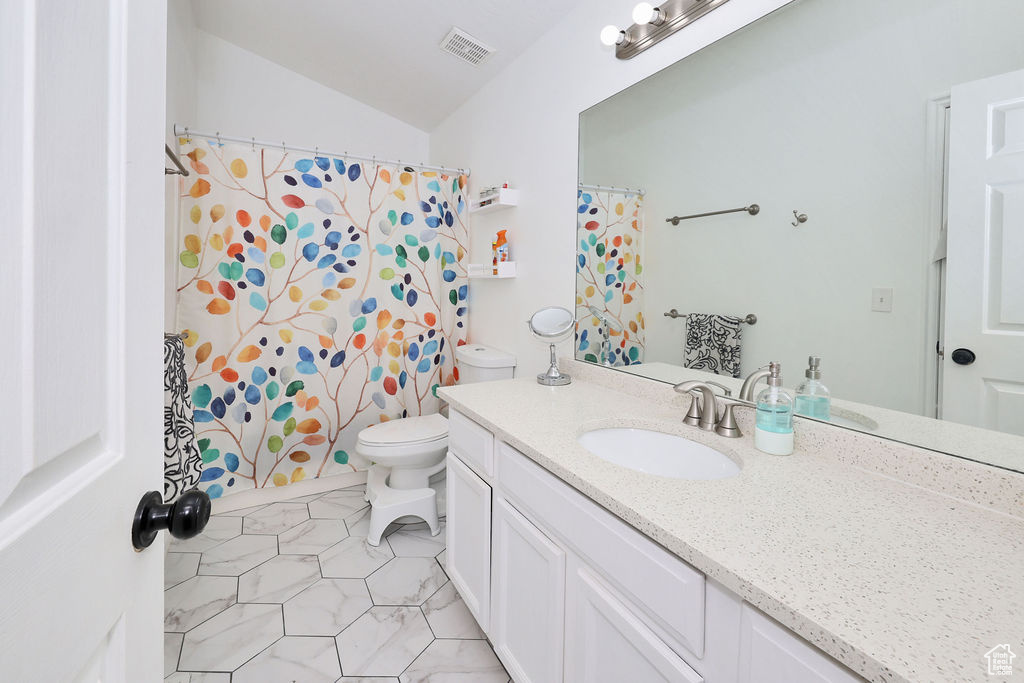 Full bath featuring toilet, vanity, tile patterned flooring, lofted ceiling, and curtained shower