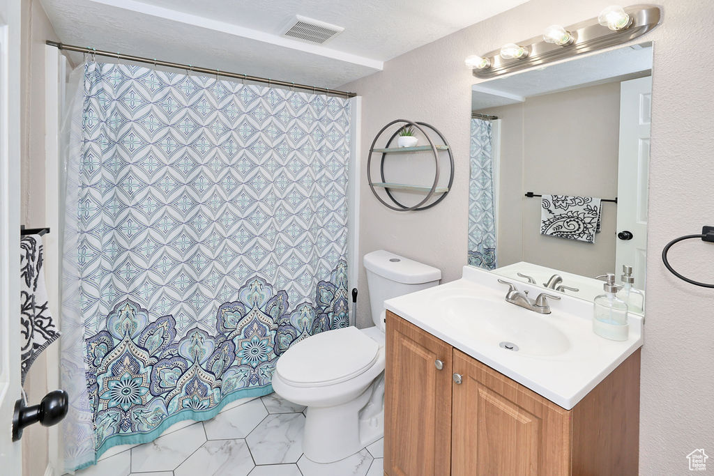 Bathroom featuring toilet, vanity, and a shower with shower curtain