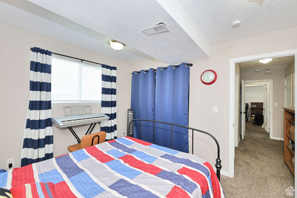 Bedroom with carpet floors, baseboards, and a textured ceiling