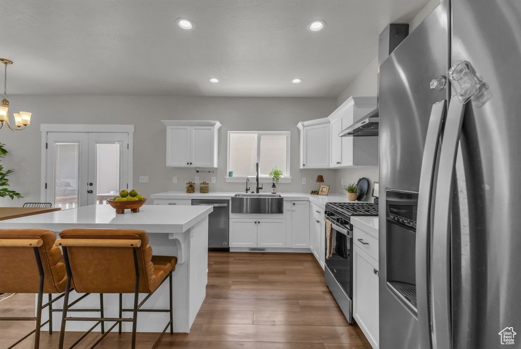 Kitchen with appliances with stainless steel finishes, a sink, a kitchen breakfast bar, white cabinetry, and recessed lighting