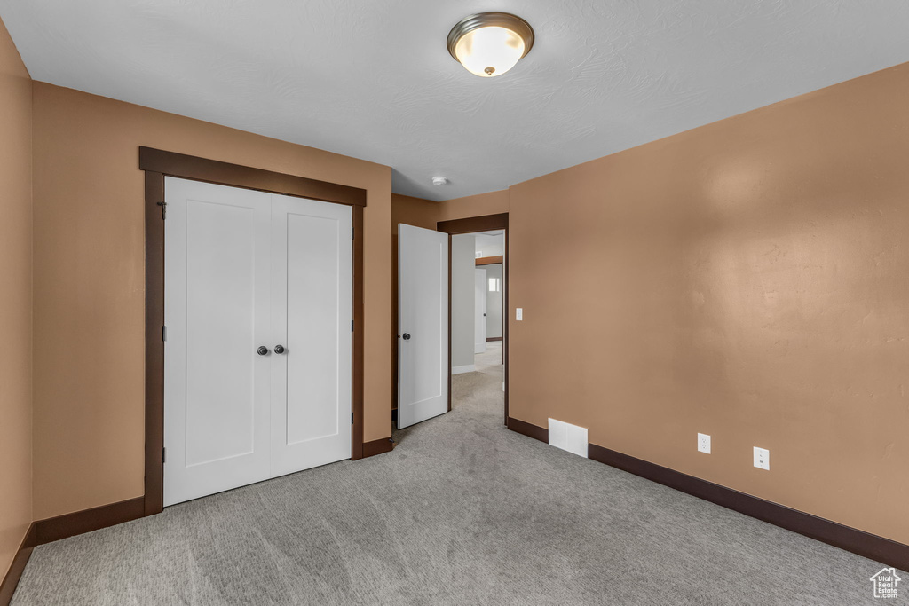 Unfurnished bedroom featuring baseboards, carpet, and a closet