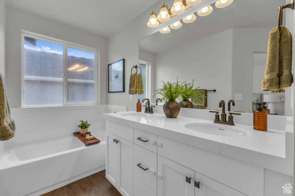 Full bath with wood finished floors, a garden tub, and double vanity