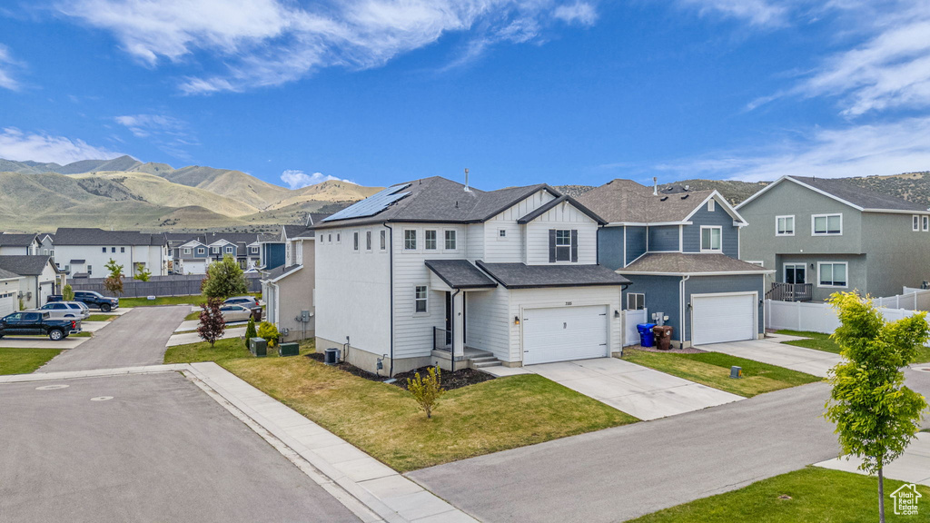 View of front of home with a residential view, a mountain view, driveway, board and batten siding, and a garage