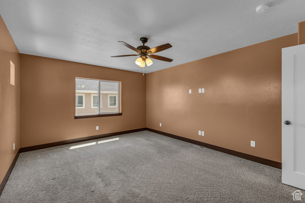 Spare room with baseboards, a ceiling fan, a smoke detector, and carpet flooring