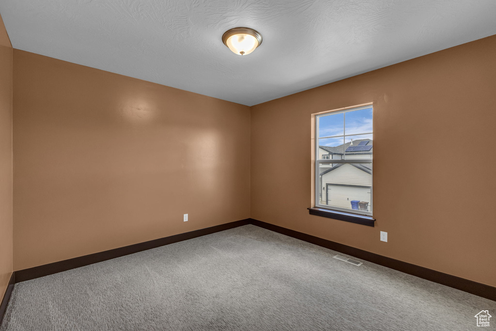 Carpeted spare room featuring baseboards