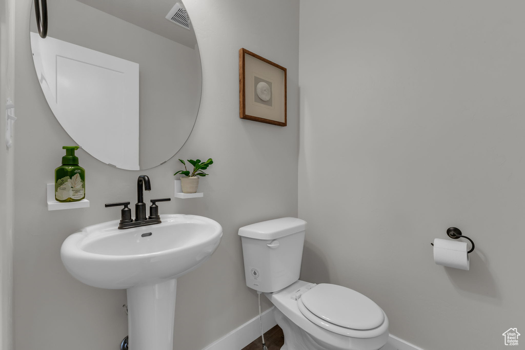 Half bath featuring baseboards, toilet, and a sink