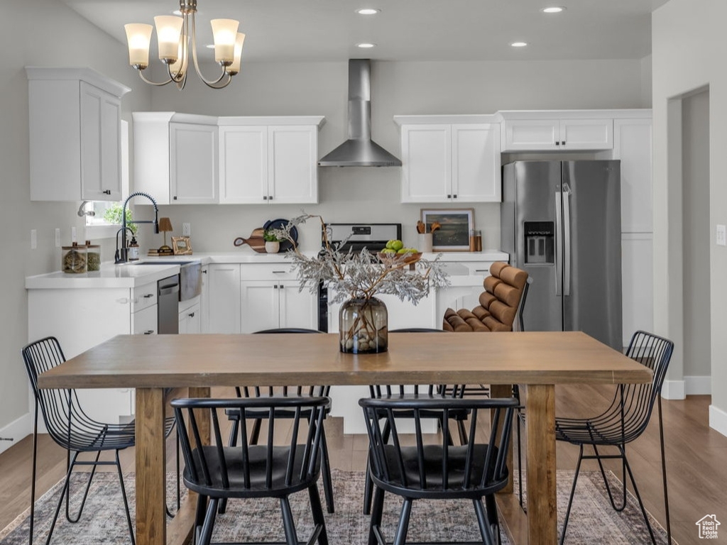 Dining space with a chandelier, baseboards, wood finished floors, and recessed lighting