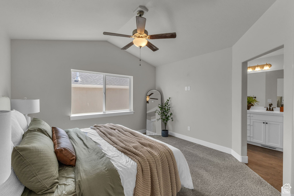 Bedroom featuring lofted ceiling, ensuite bathroom, baseboards, a sink, and a ceiling fan