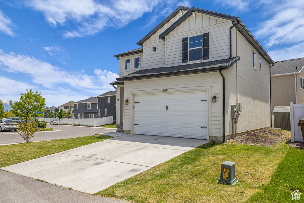 View of front facade featuring a garage, driveway, board and batten siding, and a residential view