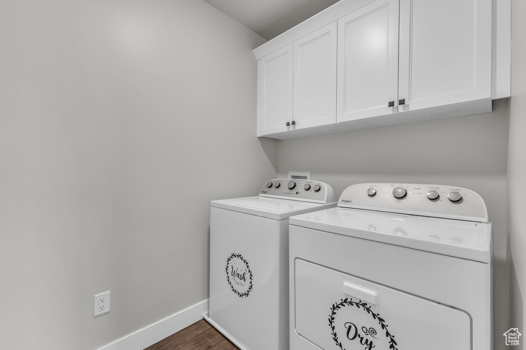 Laundry area with washer and dryer, cabinet space, baseboards, and dark wood-style flooring