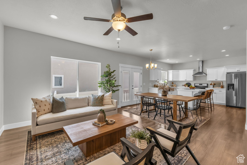 Living area with ceiling fan, wood finished floors, a chandelier, baseboards, and recessed lighting