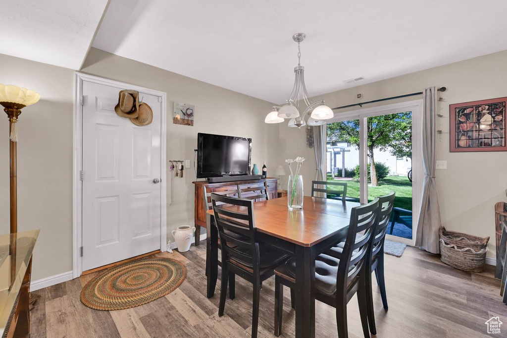 Dining room with wood finished floors, a chandelier, and baseboards