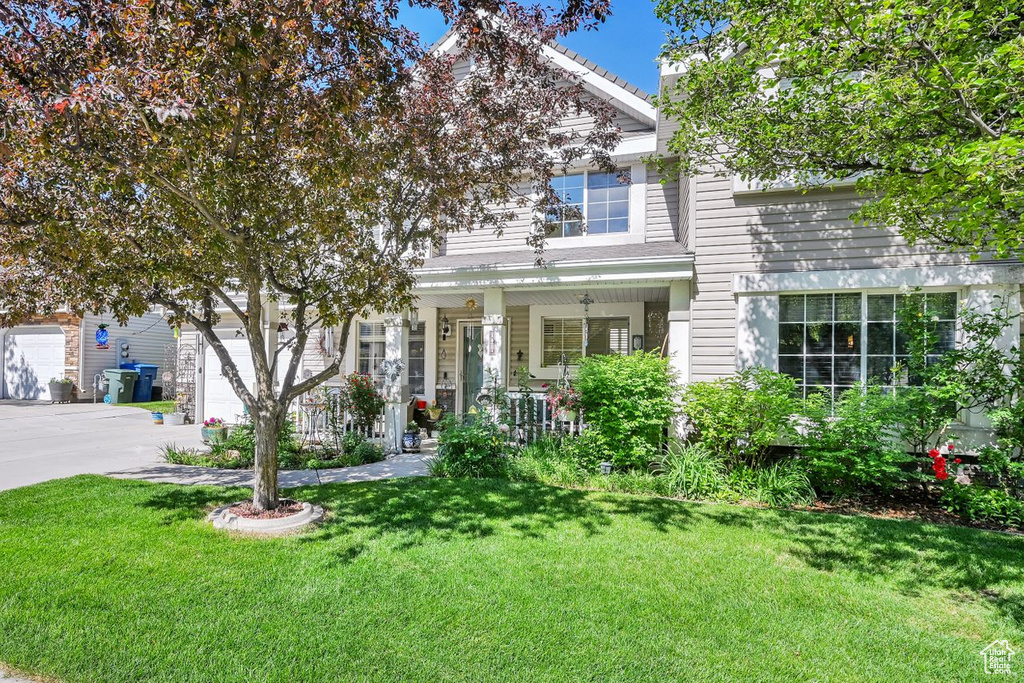 View of front of property with covered porch, a front lawn, concrete driveway, and a garage