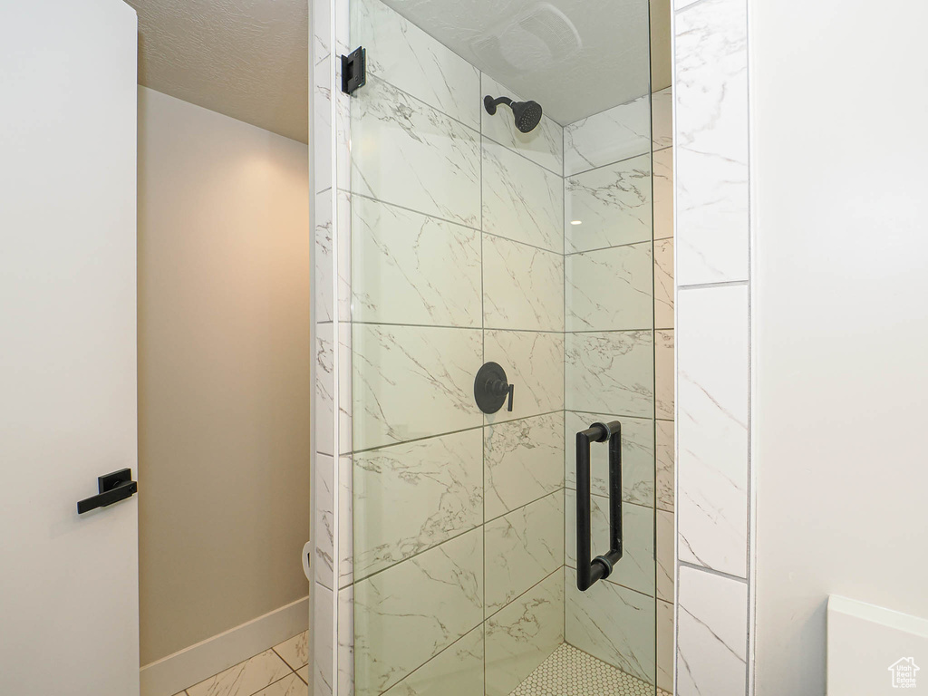 Full bathroom with a shower stall, marble look tile flooring, and baseboards