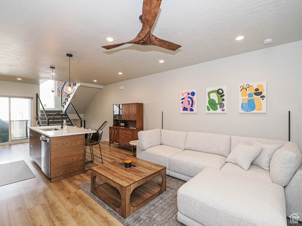 Living area featuring light wood-style flooring, recessed lighting, a textured ceiling, stairs, and ceiling fan
