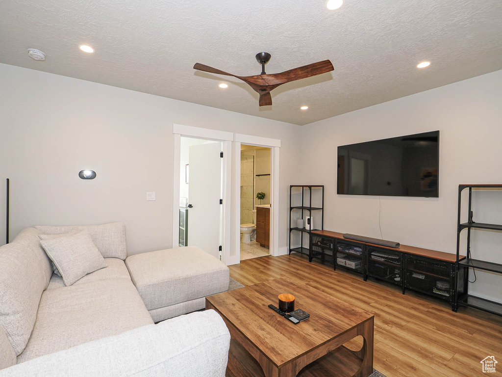 Living area with a ceiling fan, wood finished floors, recessed lighting, and a textured ceiling
