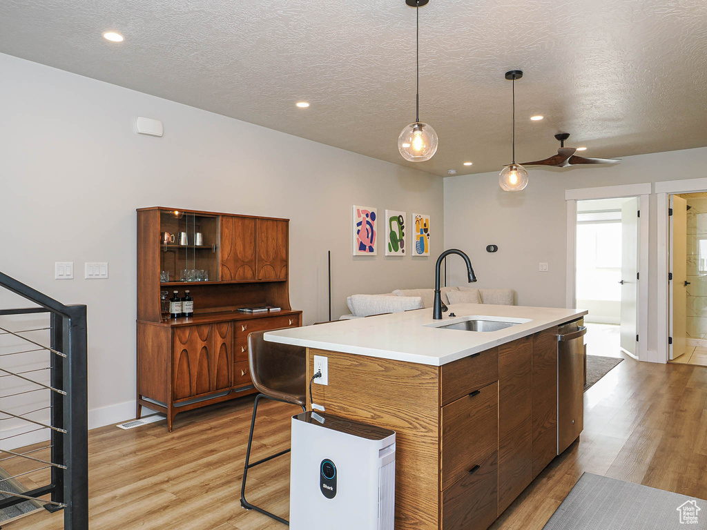 Kitchen with a sink, dishwasher, brown cabinetry, light wood-style flooring, and recessed lighting