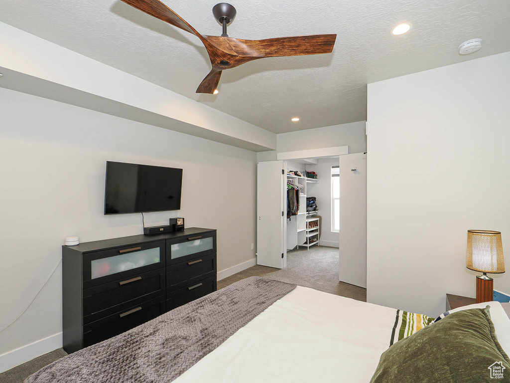 Bedroom featuring carpet, baseboards, a walk in closet, a ceiling fan, and recessed lighting