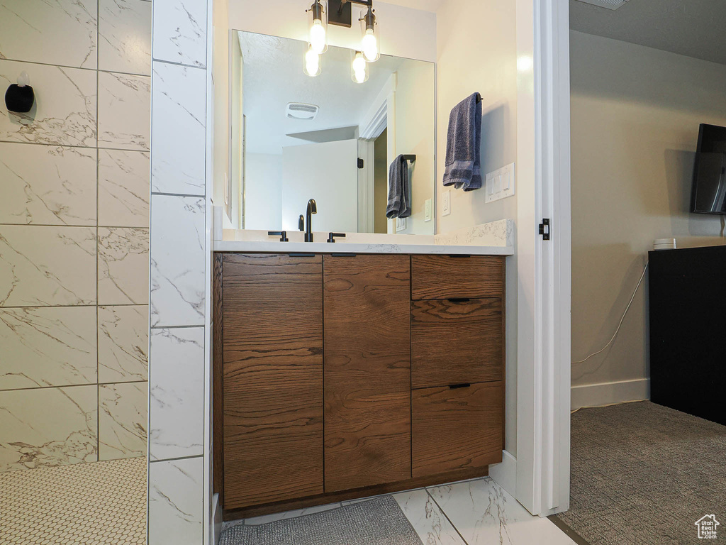 Full bathroom with marble finish floors, vanity, and walk in shower