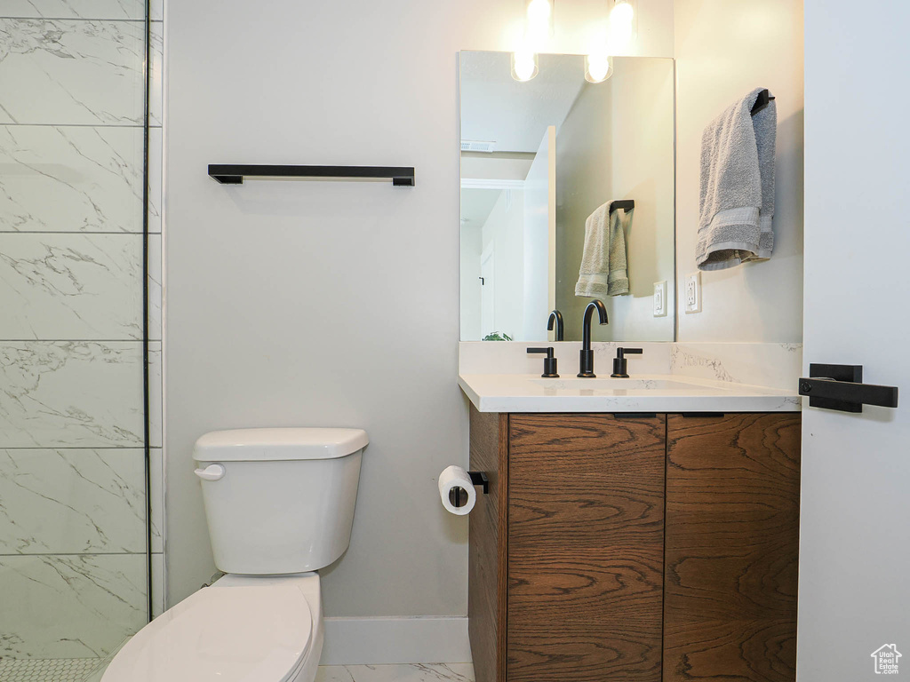Full bathroom featuring marble look tile flooring, toilet, vanity, and baseboards