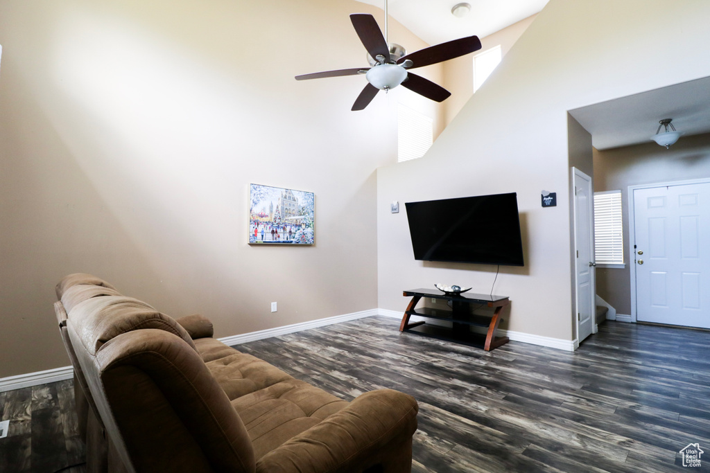 Living area featuring wood finished floors, a high ceiling, a ceiling fan, and baseboards