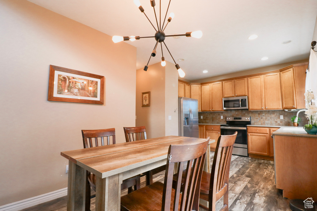 Kitchen featuring appliances with stainless steel finishes, backsplash, a chandelier, dark wood-type flooring, and recessed lighting