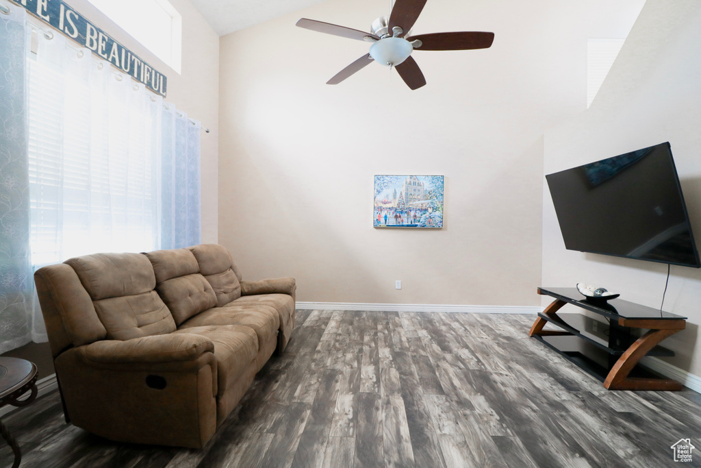 Living area featuring a ceiling fan, wood finished floors, baseboards, and high vaulted ceiling