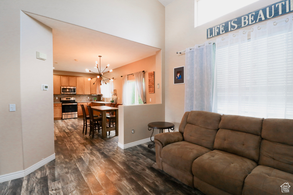 Living room featuring a chandelier, dark wood-type flooring, and baseboards